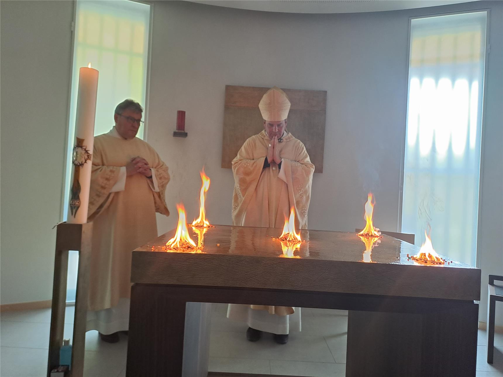 Zwei Personen stehen hinter einem Altar mit vier Flammen an den jeweiligen Ecken.