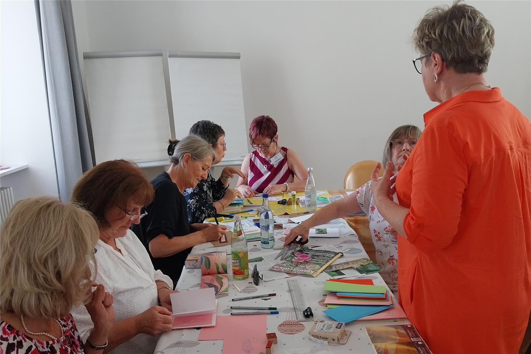 Eine Gruppe von Frauen sitzt um einen Tisch und arbeitet mit Papier und Scheren.