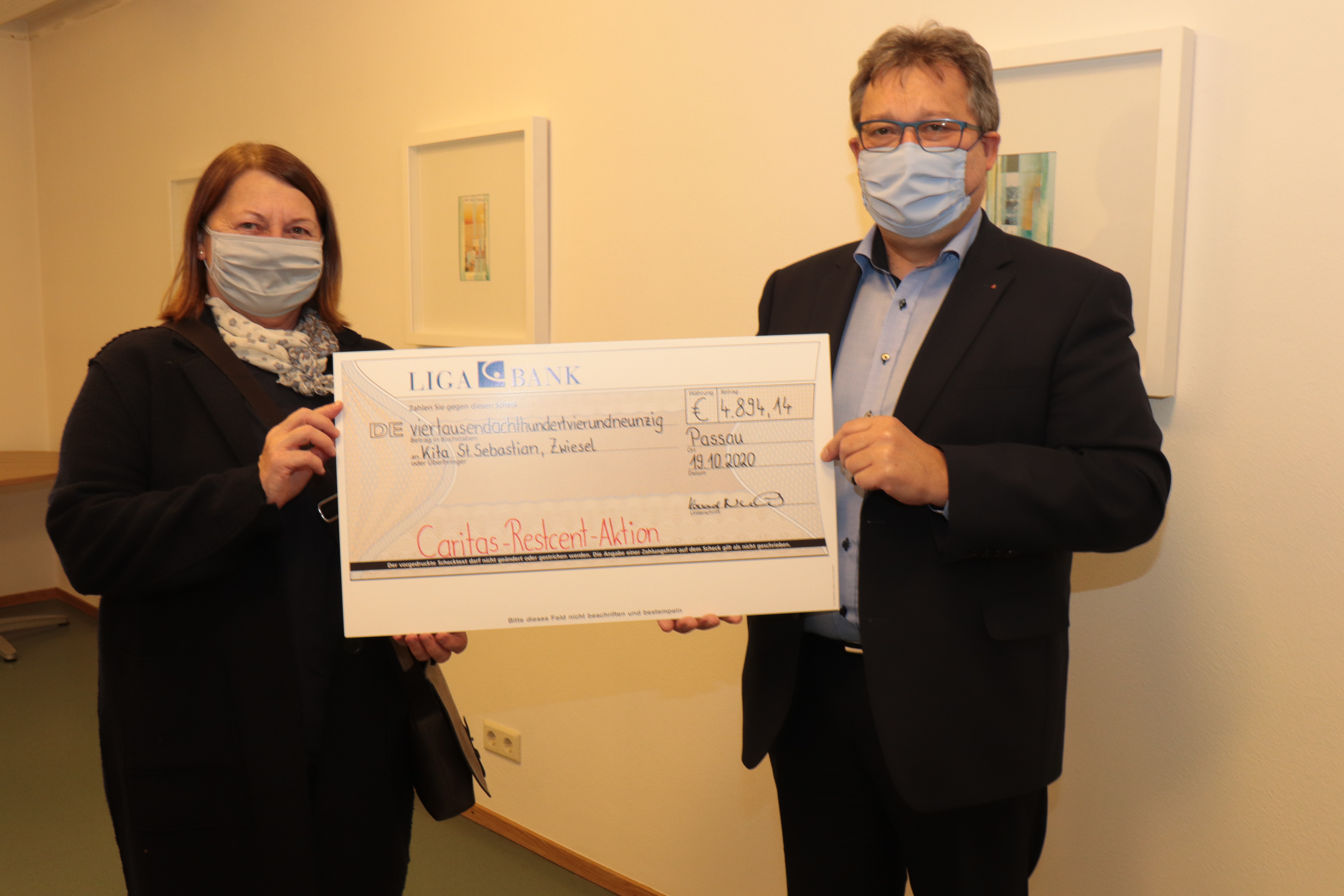 Ein Mann übergibt einer Frau einen großen Spenden Check