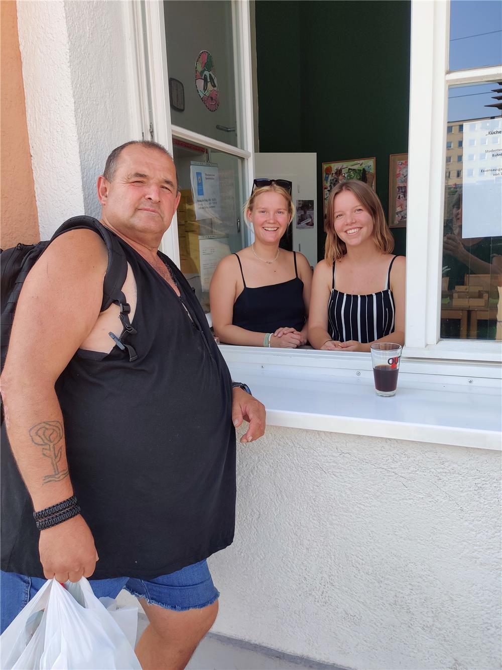 zwei junge Damen geben Essen an einen obdachlosen Mann