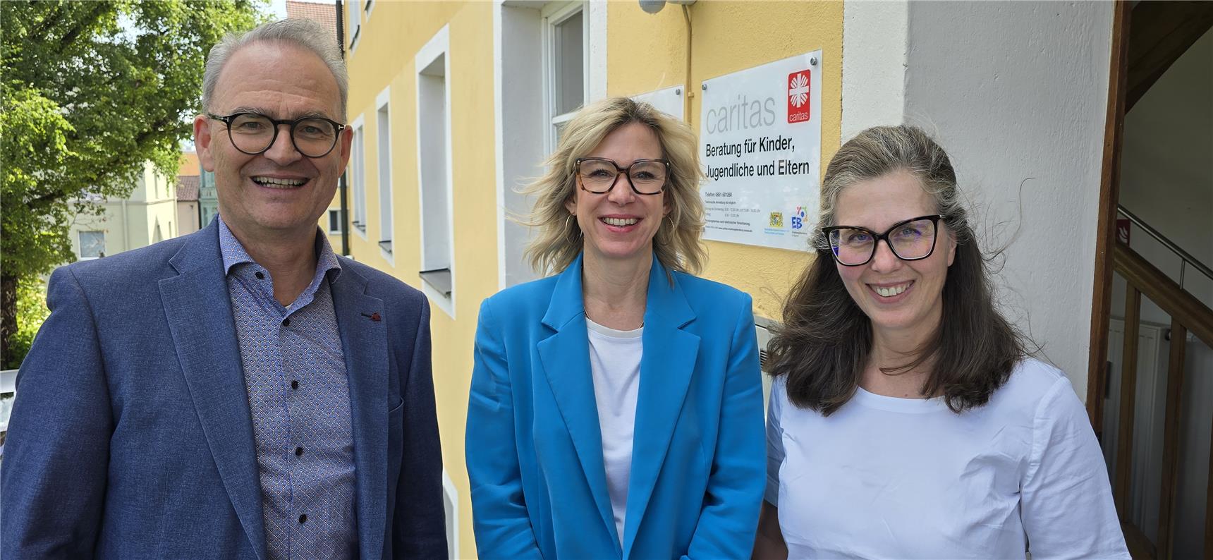 Drei Personen stehen vor einem Gebäude und posieren für ein Foto.