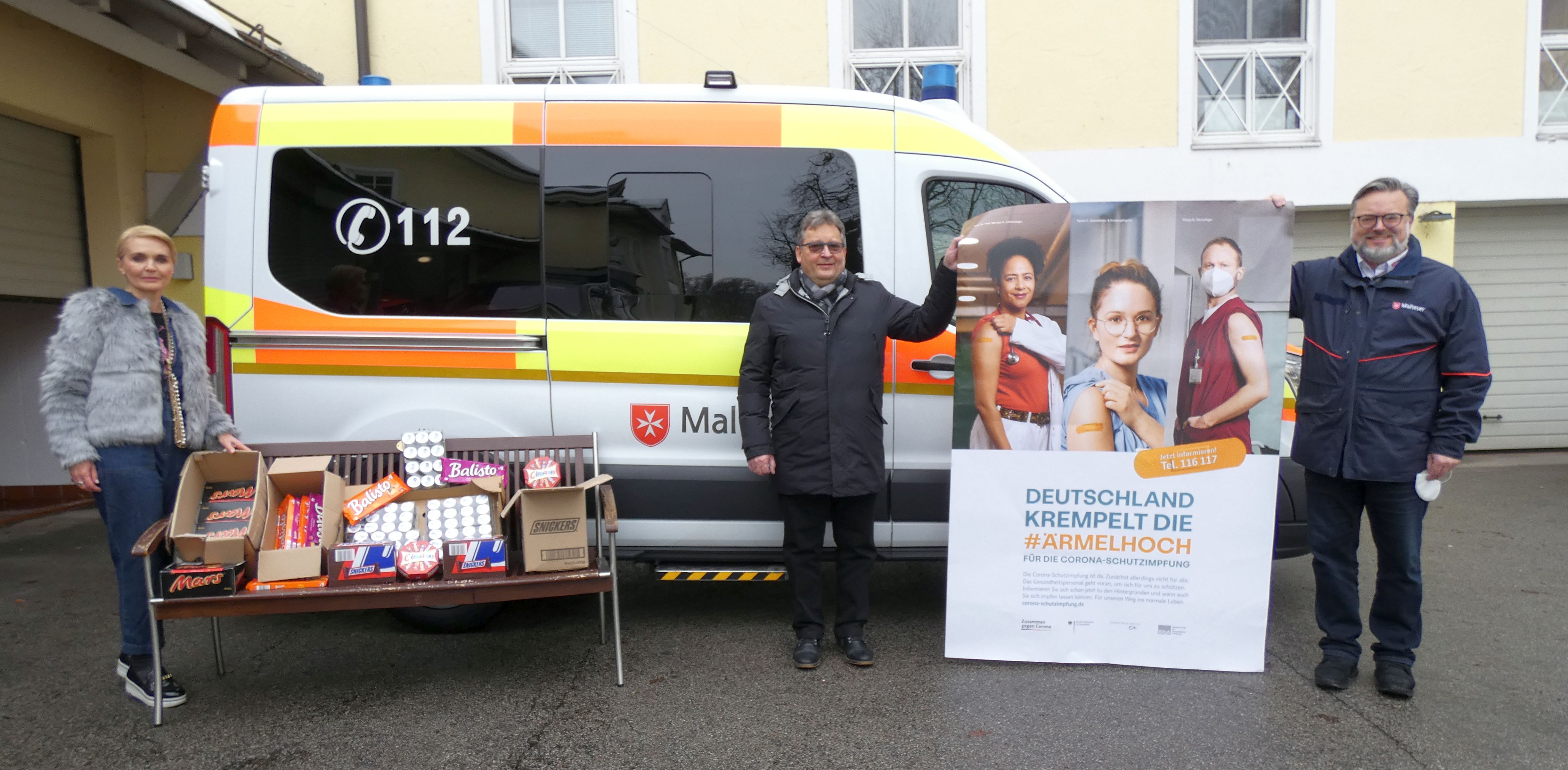 eine Dame und zwei Herren halten das Impfplakat