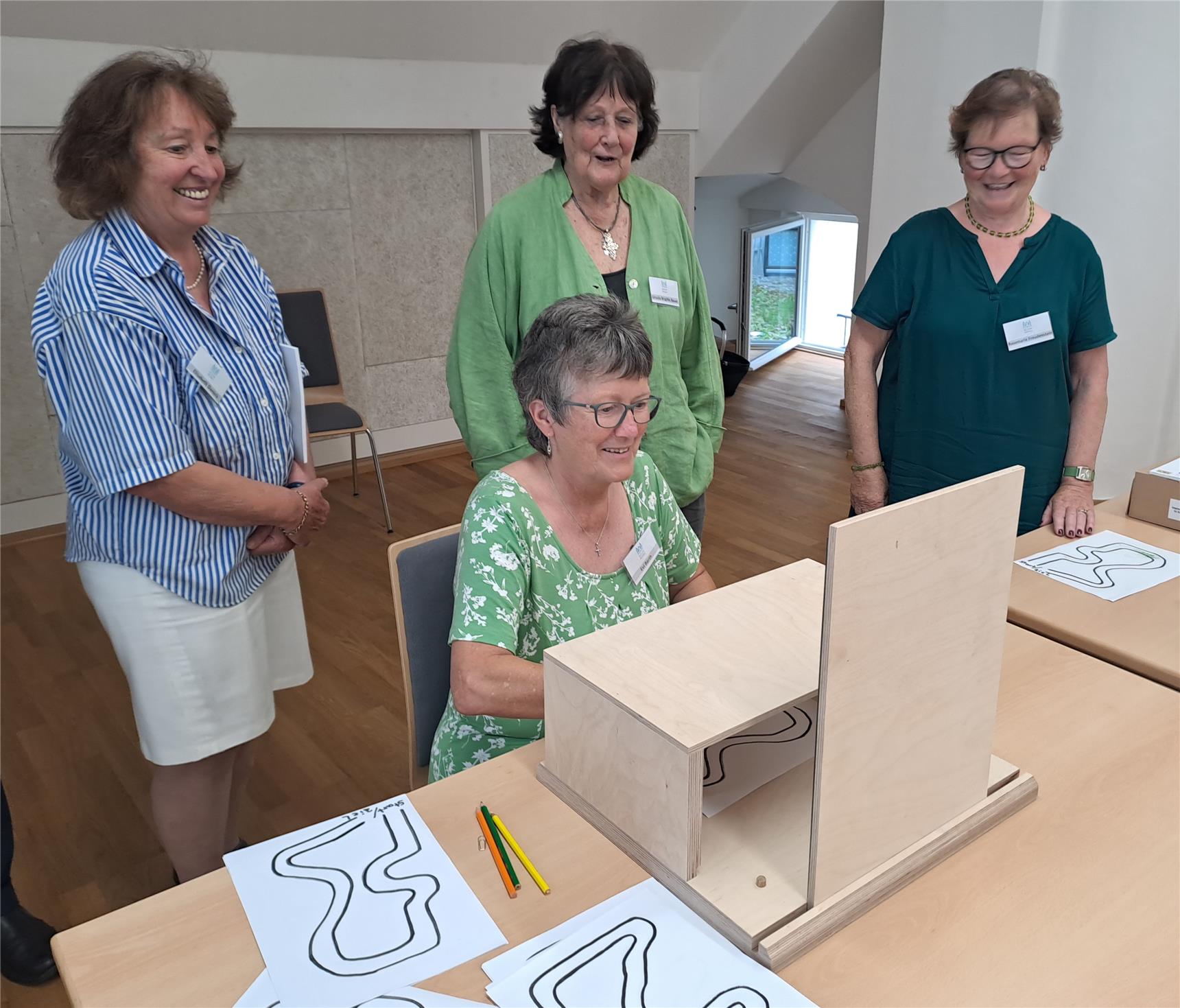 Mehrere Frauen stehen um einen Tisch mit einer Box, während sie miteinander sprechen und sich austauschen.