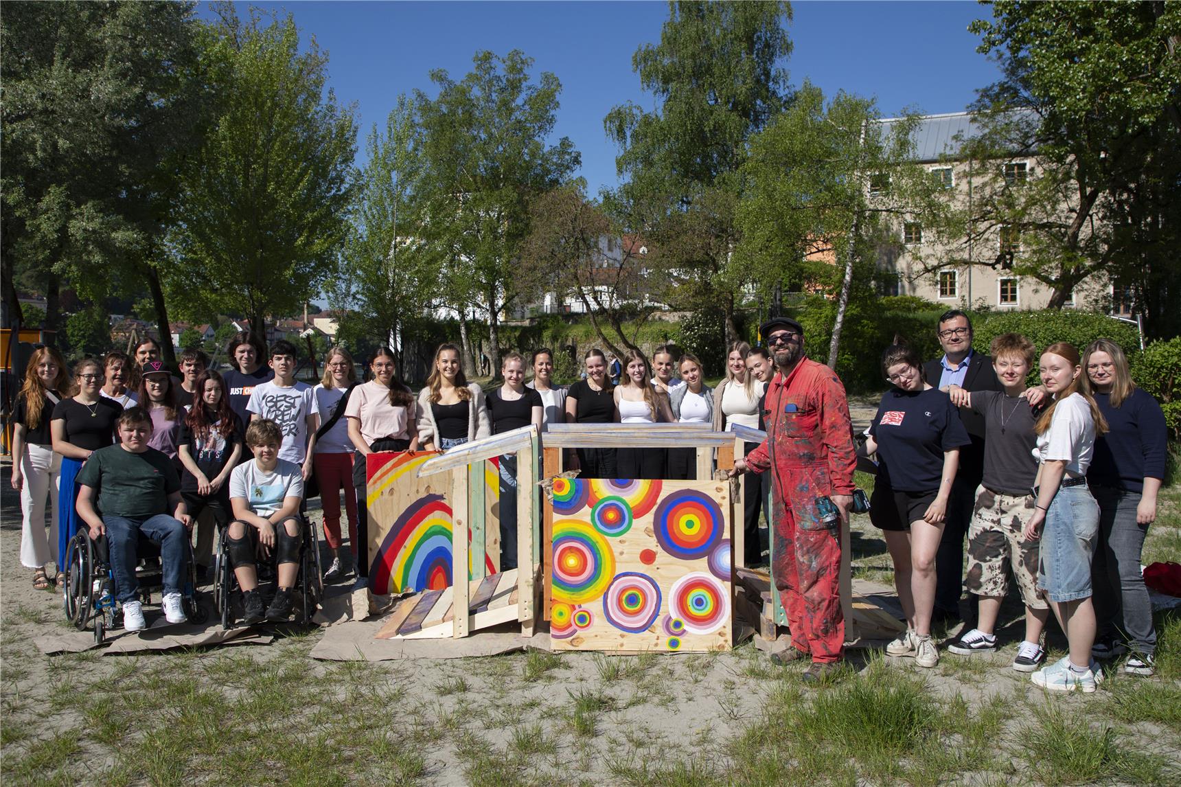 Viele Personen stehen um eine bunt dekorierte Holzbrücke.