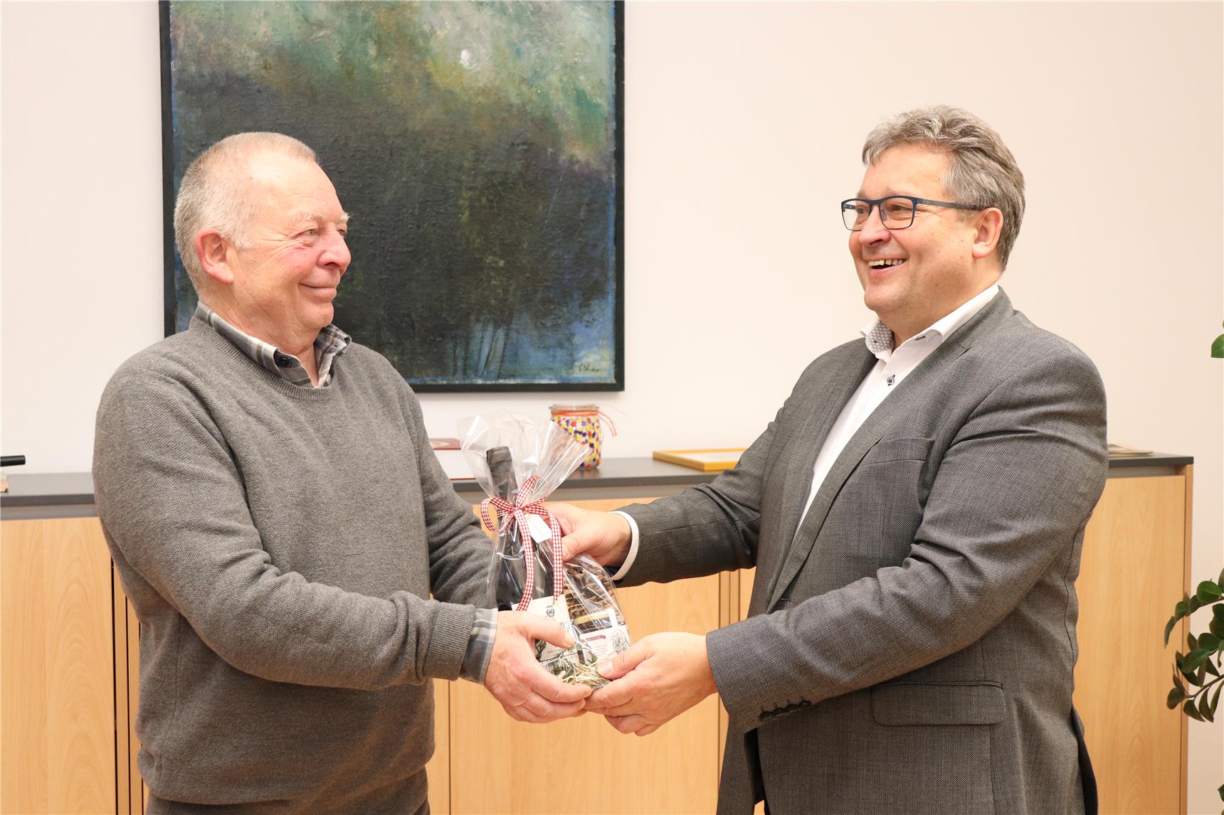 ein Herr überreicht dem ausscheidendem Mitarbeiter ein Geschenk