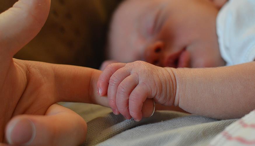 Schlafendes Baby hält sich an Finger fest