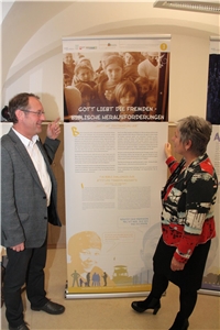 Wanderausstellung 'Gott liebt die Fremden' - Ingrid Aldozo-Entholzner und Konrad Haberger von der Abteilung Gemeindecaritas Konrad Haberger und Ingrid Aldozo-Entholzner vor einem Ausstellungsplakat