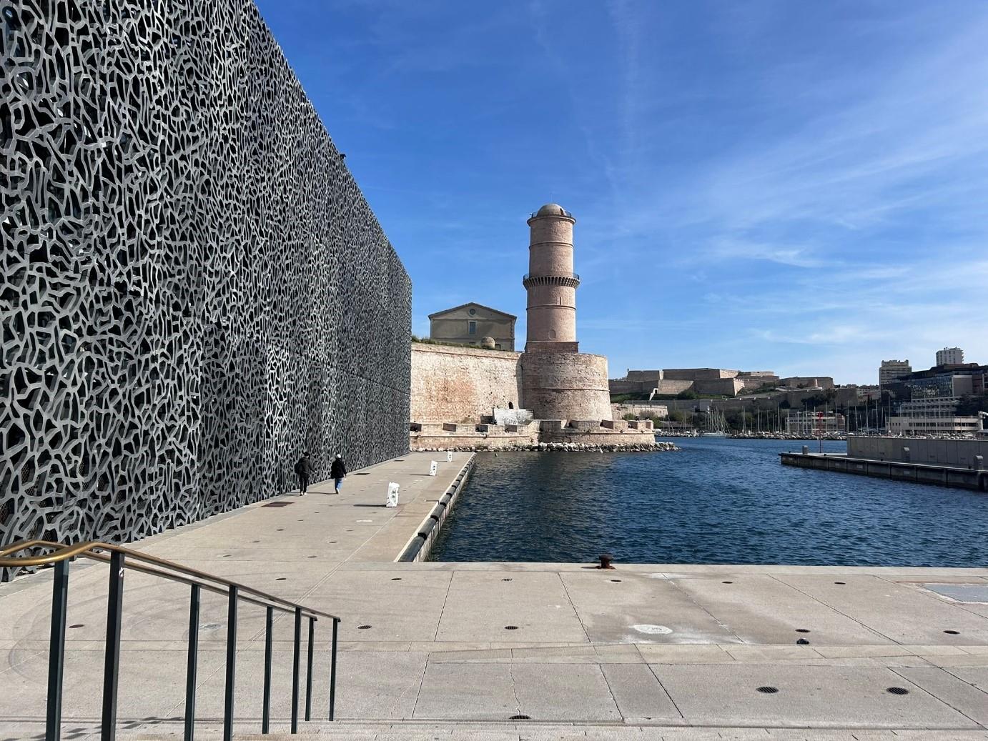 Ein Wasserturm mit historischem Design und Blick auf die Stadtlandschaft. Links im Bild eine Mauer mit malerischer Architektur.