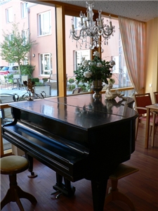 Konzertflügel mit Rosenstrauß und Kronleuchter im Speisesaal