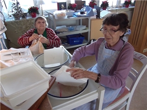Zwei Bewohnerin beim Abwaschen an einem alten ausziehbaren Abwaschtisch mit Emailschüsseln.