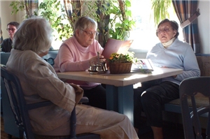 Drei Bewohnerinnen sitzen zusammen am Tisch in einem Café.