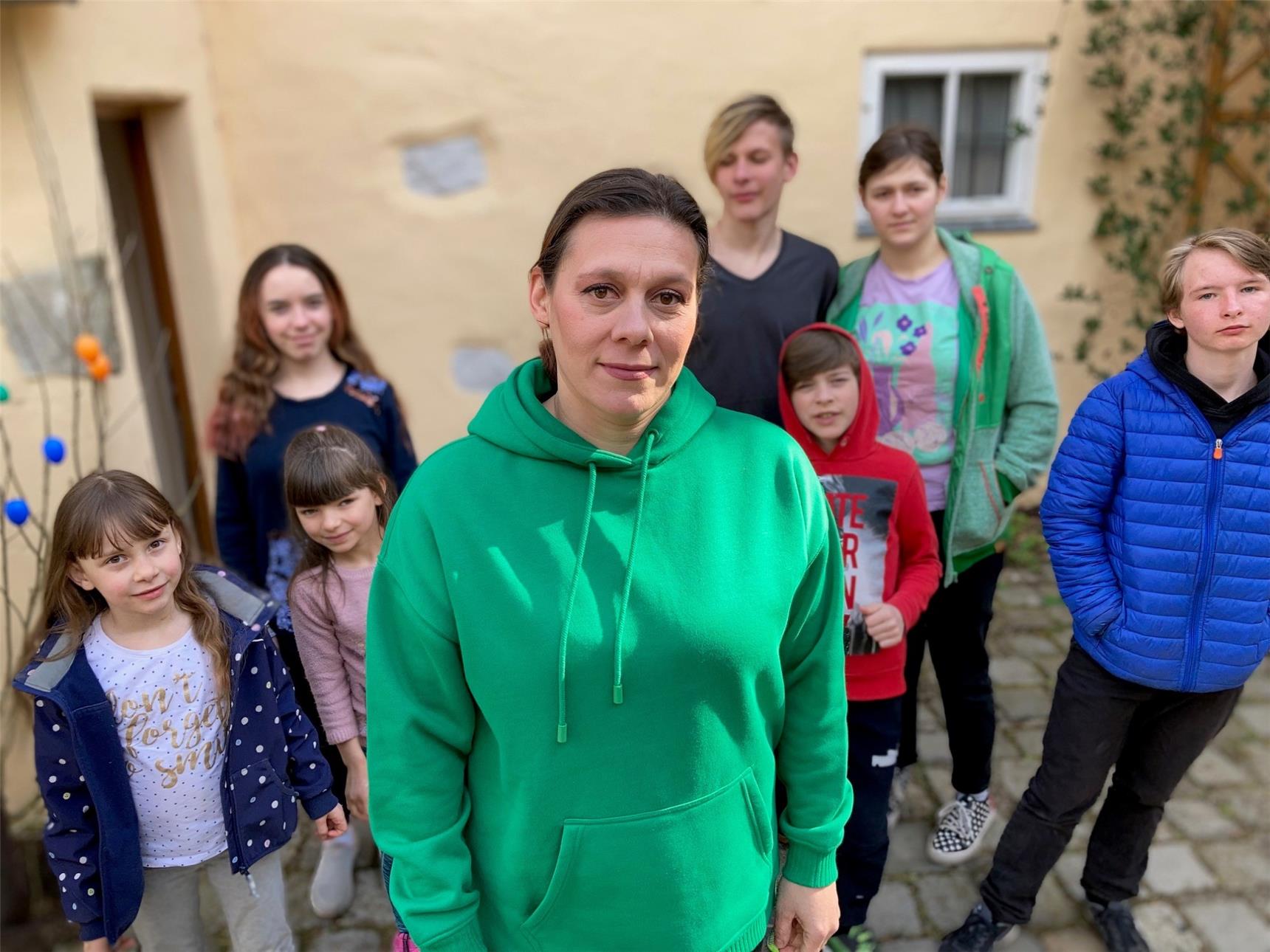 eine Frau mit Kindern vor einem Haus