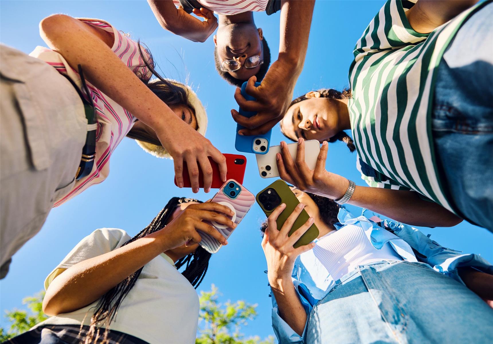 Jugendliche blicken im Freien auf ihre Smartphones