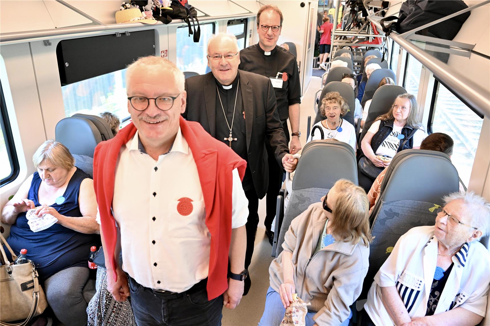 Ein Zugabteil gefüllt mit Menschen im Gang stehen drei Männer