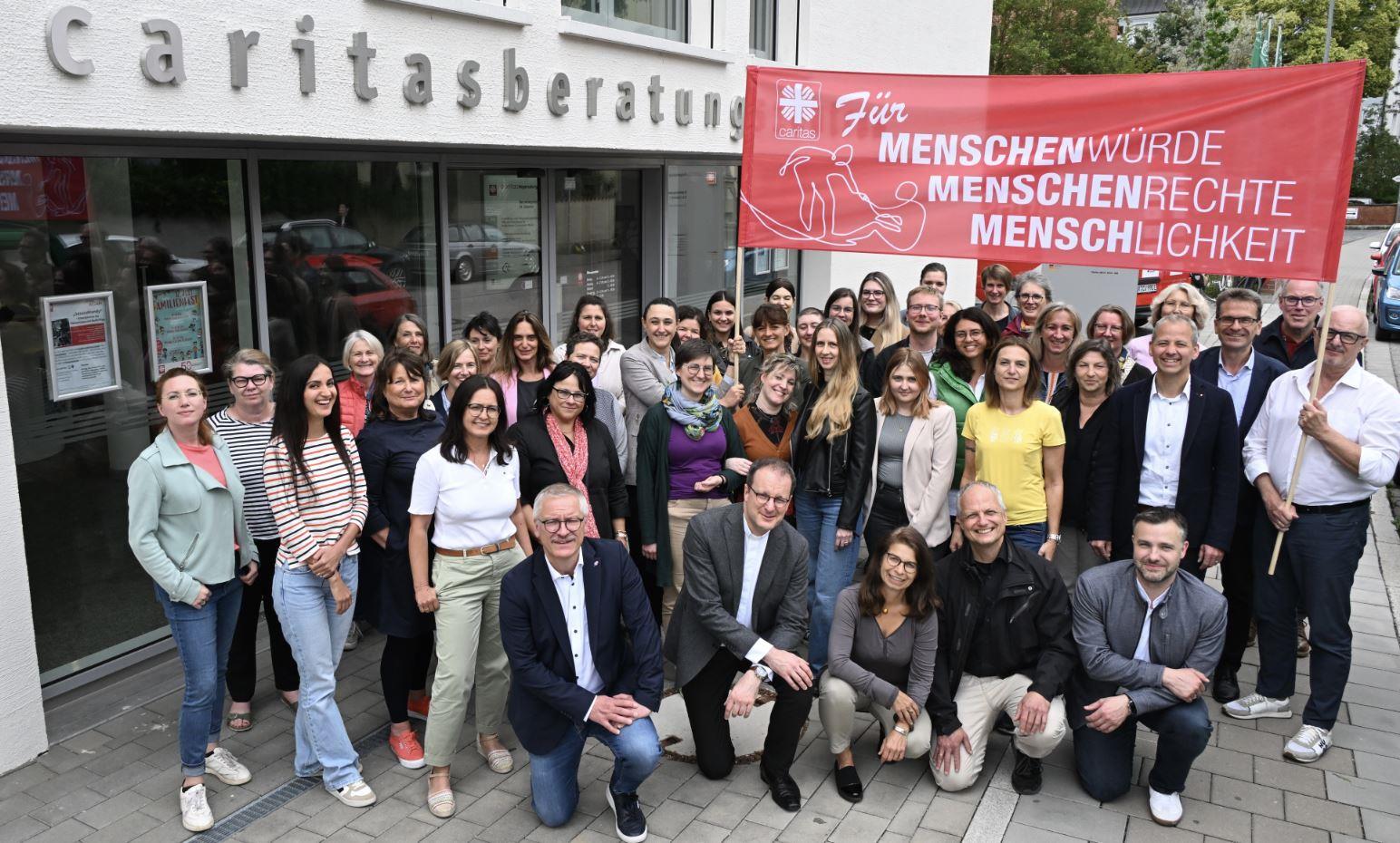 Mitarbeiter der Caritas Regensburg vor dem Beratungszentrum mit großem Banner