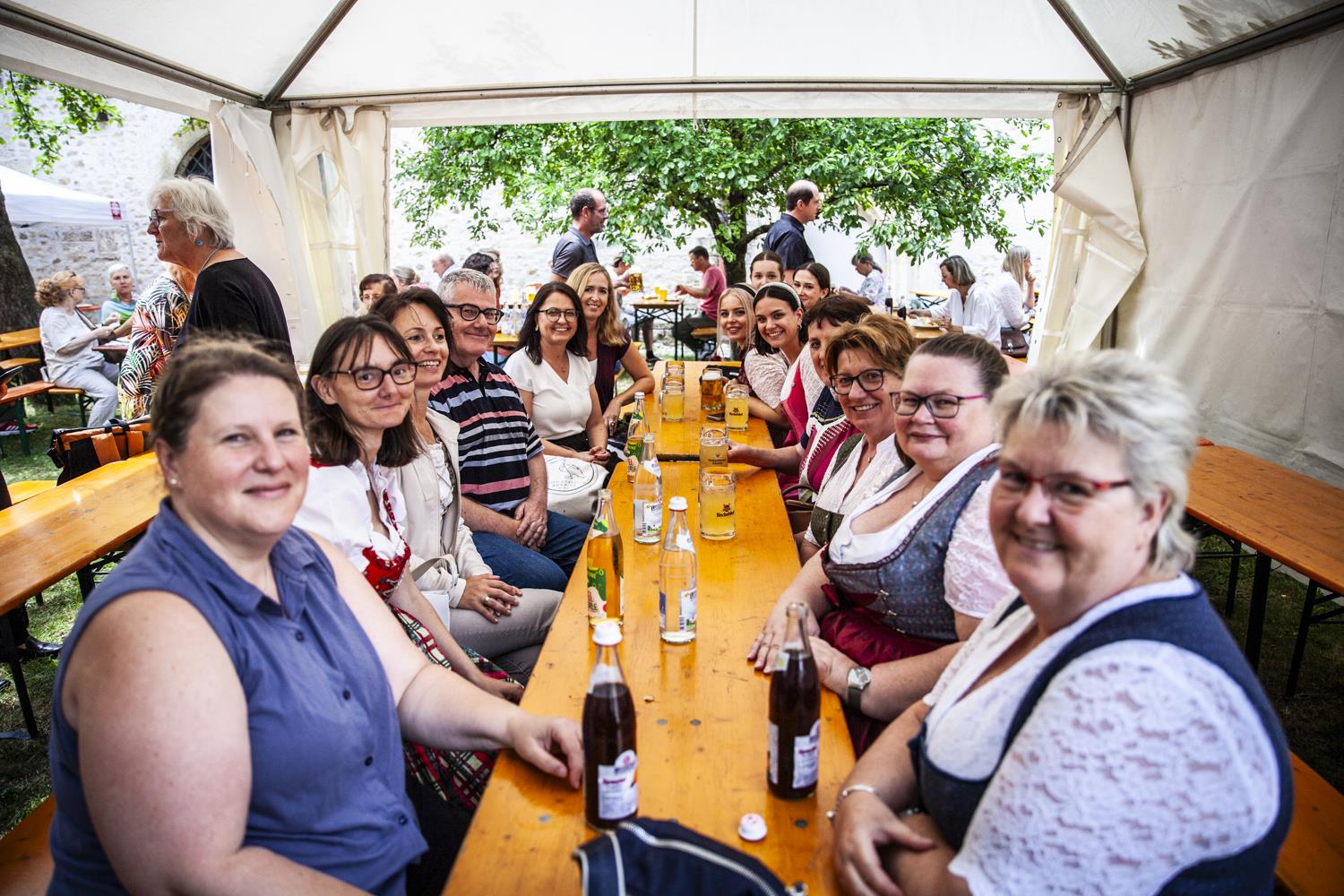 Mitarbeiterinnen im Dirndl gemeinsam am Tisch im Garten