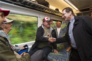 Diözesan-Caritasdirektor Dr. Roland Batz schüttelt Gästen im Zug die Hand.