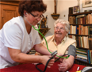 Arbeitsgemeinschaft Altenhilfe Seniorin bekommt den Blutdruck gemessen.