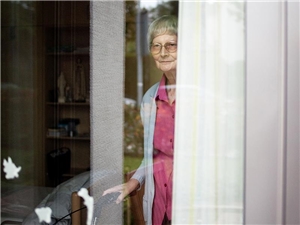 Caritasausschuss Hospiz Ältere Dame schaut zum Fenster heraus.