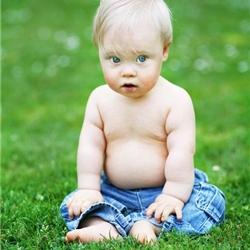 Ein Baby sitzt auf einer grünen Wiese