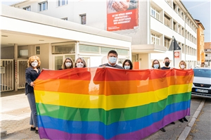 Vier Personen halten eine Fahne in den Farben des Regenbogens