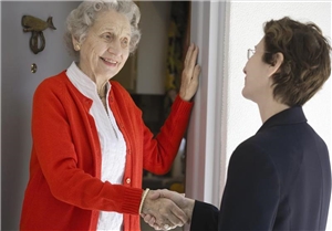 Eine ältere Frau steht in der offenen Tür und gibt einer jüngeren Frau die Hand.