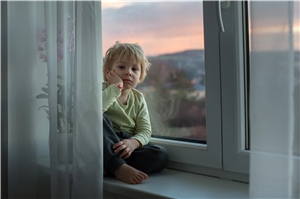 Ein Junge sitzt auf einer großen Fensterbank
