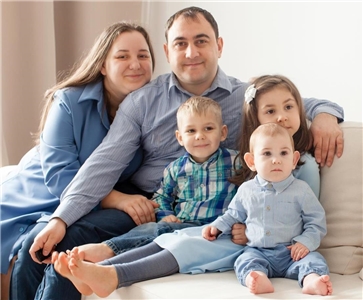 Ein Ehepaar mit drei Kindern sitzt auf einem Sofa
