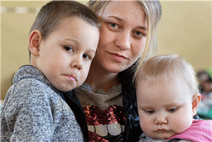 Eine ukrainische Mutter mit ihren beiden Kindern im Arm. Angekommen in einer Caritas Unterkunft für Geflüchtete.