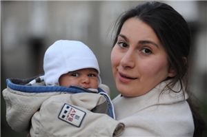 Eine Frau hält ihr Baby im Arm und schaut in die Kamera. Eine Frau hält ihr Baby im Arm.