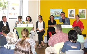 Auf dem Bild sind die Personen der Podiumsdiskussion zu sehen und ein Teil des Publikums
