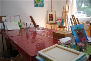 Raum mit rotem Tisch und Malutensilien