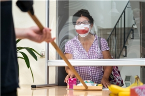 In der Tagesstätte für Wohnungslose Olga46 wird Essen ausgegeben. Die Empfängerin trägt eine Mund-Nasen-Schutz Maske.
