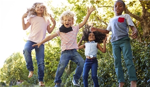 Vier Kinder haben Spaß zusammen auf einem Trampolin im Garten