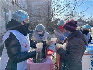 Eine Caritas-Helferin versorgt Flüchtlinge aus der Ukraine mit einer heißen Suppe.
