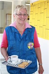 Eine ehrenamtliche Helferin der Bahnhofsmission Koblenz bietet einen Kaffee an.
