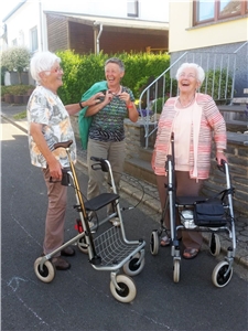 Drei ältere Frauen stehen zusammen und lachen.