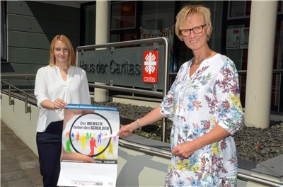 Für die Schuldnerberatung der Caritas zählt der „Mensch hinter den Schulden“. Bereichsleiterin Annika Schuhmacher (l.) und Schuldnerberaterin Elisabeth Mankertz mit dem Plakat der Aktionswoche.