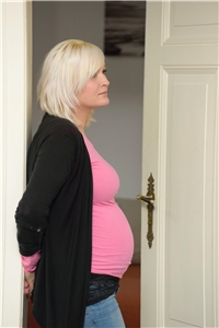 Schwangere Frau im Türrahmen