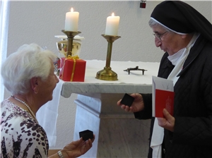 eine Ordensschwester überreicht der Jubilarin kleine Dose mit dem Kreuz 