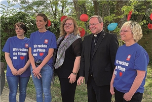 Der Bischof steht mit vier Frauen vor einem Baum.