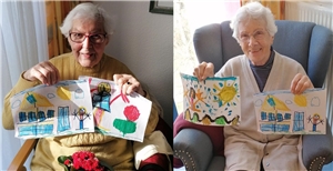 Zwei Bewohnerinnen präsentieren die Bilder, die ein kleines Mädchen für sie gemalt hat