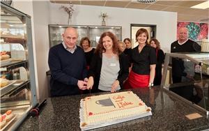 Einrichtungsleiterin Getrud Schwickert und Sozialraummanager Heiko Hastrich schneiden die Torte mit der Aufschrift Café Nächstenliebe an.