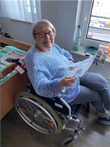 Eine Seniorin im Rollstuhl liest ihren Brief