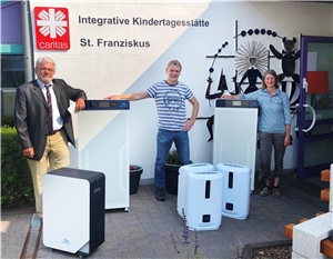 Peter Roos, Matthias Baun und Elke Kühlem zeigen einen Teil der Luftreinigungsgeräte vor der Kita.