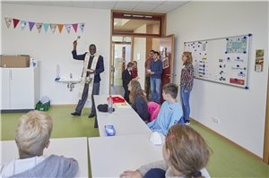 Pfarrer Robert Butele segnet die neuen Räumlichkeiten der Katharina-Kasper-Schule ein. Die Schüler schauen zu.