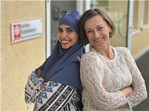 Bouchra Bouziane und Halyna Filias lachen in die Kamera und stehen vor der Caritas-Sozialstation in Ransbach-Baumbach.