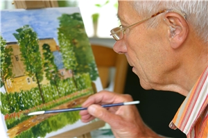 Älterer Mann mit Hörgerät beim Malen