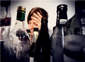 vor einer Frau stehen leere ausgetrunkene Alkoholflaschen