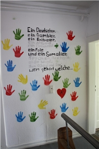 eine mit bunten Händen und Text gestaltete Wand der Wohngruppe